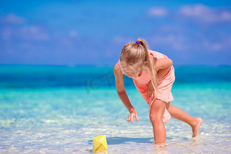 可爱的小女孩在绿松石海中玩折纸船