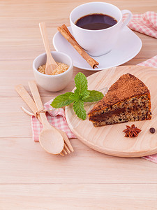 黑森林小蛋糕摄影照片_自制黑巧克力蛋糕，木制背景板上有一杯咖啡