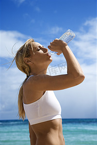 女人在海滩上喝水。