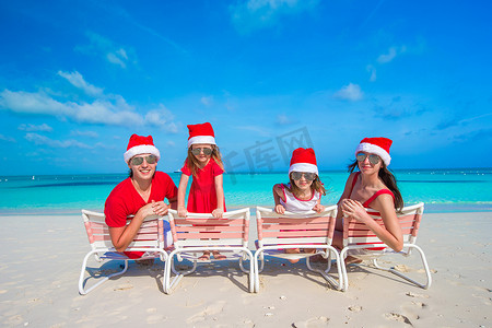 戴着圣诞帽的家庭在热带海滩上玩得开心