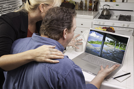 房地产意境摄影照片_夫妇在厨房使用笔记本电脑 - 房地产和假期