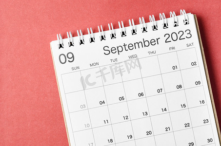 红色2023背景摄影照片_2023 年 9 月的日历台，供组织者在红色背景中进行计划和提醒。