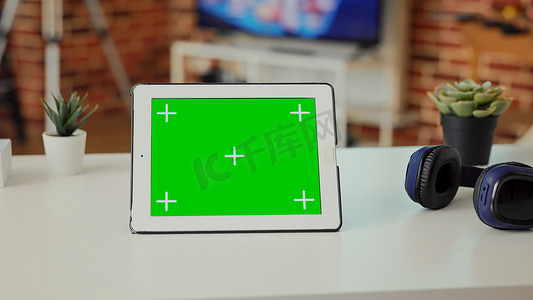 平板电脑绿幕摄影照片_带有显示绿色屏幕的数字平板电脑的空桌子