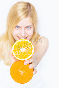 年轻的金发女郎拿着橙色水果，微笑着，健康地吃着