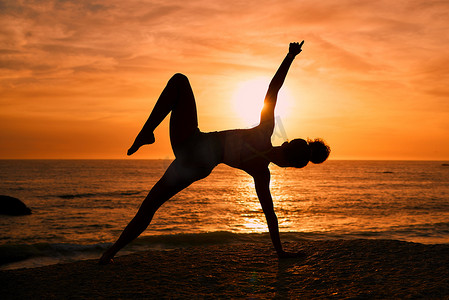 健身、瑜伽和日出时在海滩上进行锻炼、训练和普拉提锻炼的女性剪影。