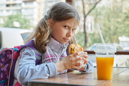 户外肖像漂亮女学生 8、9 岁，带芝士汉堡和橙汁