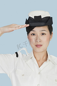 海军敬礼摄影照片_一位美丽的年轻美国海军军官在浅蓝色背景中敬礼的画像