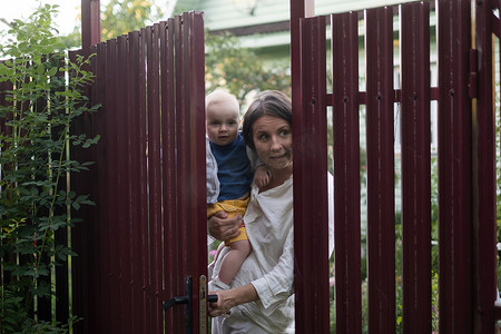 近邻摄影照片_带着婴儿的好奇女人偷看栅栏门
