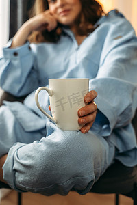 热手摄影照片_一个女人的膝盖上放着一杯白茶或咖啡。
