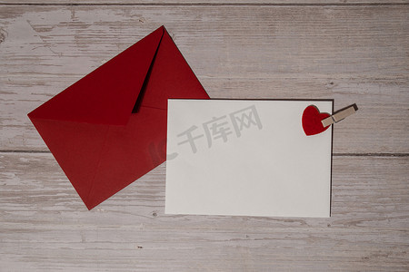 红色邀请卡摄影照片_问候卡或邀请卡模拟与木制背景上的红色信封。