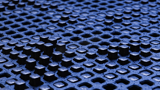 工业蓝色背景摄影照片_黑色石墨立方体的蓝色背景。 