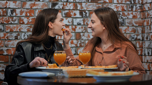 年轻女孩在咖啡馆吃饭，互相喂食。