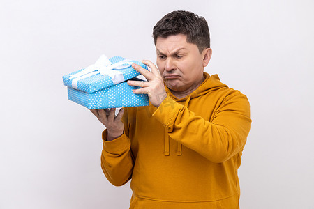 不满意的男人手里拿着打开的礼盒，对内容感到沮丧，礼物不好。