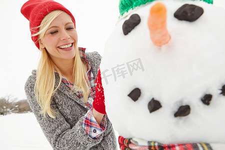 在英国，冬天、雪和女人在圣诞节期间在户外快乐地堆雪人。
