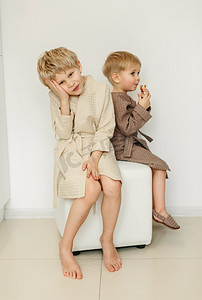 两个穿着浴袍的男孩坐在白色房间的坐垫上