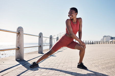 跑步运动健身摄影照片_黑人女性、伸展腿部和海滩健身以锻炼锻炼动机或跑步运动热身。
