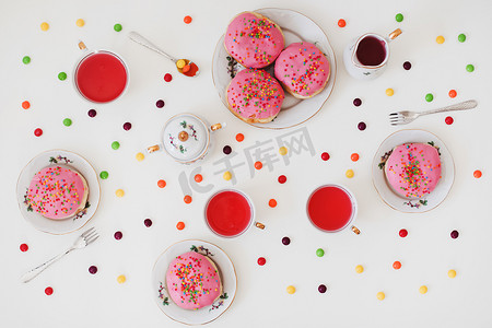 早餐，五颜六色的粉红色饮料和白桌上的甜甜圈。
