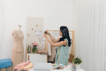手工艺人摄影照片_年轻的亚洲女时装设计师在她的工作室里测量人体模型