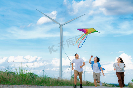 进步快乐无忧无虑的家庭度假概念与风力涡轮机放风筝