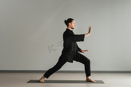 气功摄影照片_一个穿着黑色和服的男人在室内练习气功能量练习