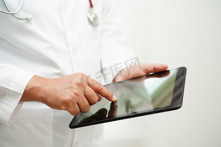 沟通方法摄影照片_亚洲女医生拿着手机或平板电脑寻找住院治疗病人的方法。