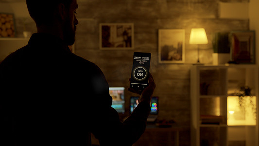男子在他的智能手机上使用声控智能灯应用程序来打开房子里的灯