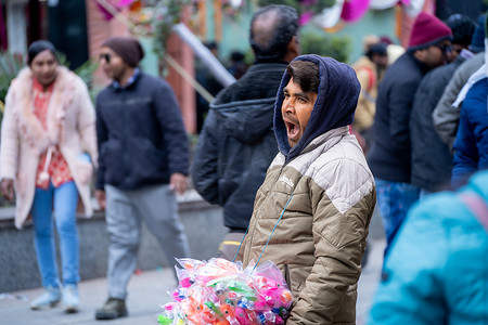 玩具小贩在 Manali 拥挤的商场路上打哈欠寻找顾客