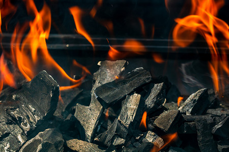 带有红色火焰、热木炭煤球和余烬的炽热明火的烧烤坑
