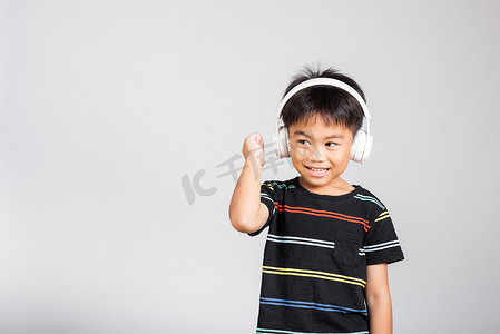 5-6 岁的小可爱男孩在孤立的工作室拍摄中用无线耳机听音乐。
