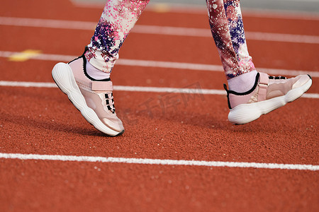 穿粉色运动鞋的女孩在体育场内奔跑
