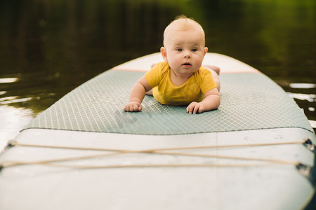 孩子躺在一个大的支撑板上漂浮在水面上。