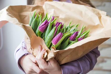 手用工艺纸包裹紫色郁金香花束，母亲节快乐，情人节礼物。