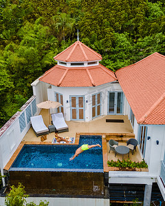 度假期间在热带泳池别墅里的情侣，无人机在热带雨林泳池平房的景色