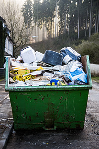 路边垃圾桶摄影照片_有废物的绿色瓦砾容器