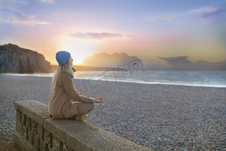 一名妇女在雪花石膏岩石和大西洋的背景下冥想