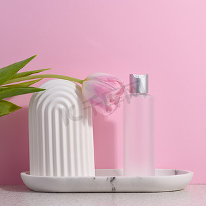 粉红色背景中用于液体化妆品的白色塑料透明瓶