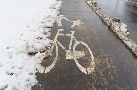 在一个下雪的冬日，路上有一个自行车标志。