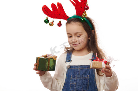 可爱的小女孩为圣诞礼物而欢欣鼓舞，圣诞礼物包裹在节日包装礼品纸中，与白色背景隔离