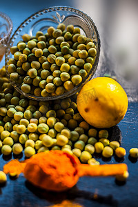 绿色面膜摄影照片_用于发光和容光焕发的皮肤的绿豌豆面膜，由黑色背景中的一些绿豌豆、蜂蜜、酸奶、姜黄、柠檬和芦荟凝胶组成。