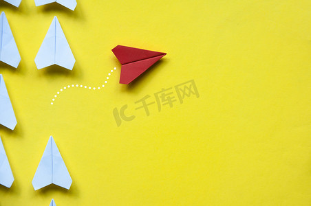 红色纸飞机折纸的顶视图将其他白色飞机留在黄色背景上，并带有可定制的文本或想法空间。