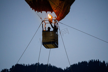 以喜马拉雅山脉为背景的柳条篮中用火加热空气的热气球篮的特写镜头，展示了库鲁马纳利山谷的这次冒险