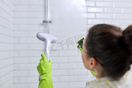 女人在浴室里打扫卫生，用淋浴蒸汽洗玻璃