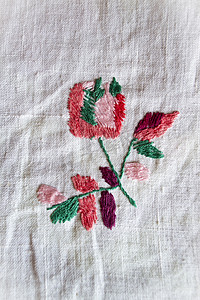 唐朝刺绣摄影照片_白色织物上的玫瑰手工刺绣光滑装饰，白俄罗斯复古民间刺绣，19 世纪下半叶