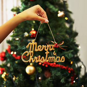 女人的手和节日的装饰，圣诞树的标志在家里客厅的背景中。