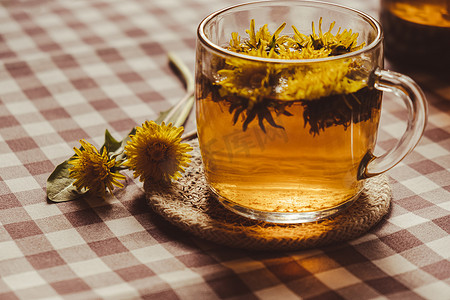 桌上玻璃杯中的蒲公英花健康茶。