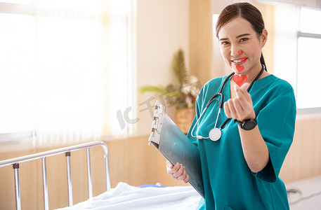 一位微笑的护士或医务人员的画像在医院里做了一个迷你心形手势