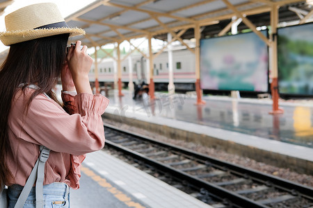 女旅客拿着相机在火车站拍照。