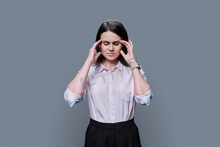 灰色背景中患有压力性头痛的年轻女性