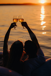 夏日傍晚，日落时分，一对幸福的情侣在海边举起眼镜的轮廓