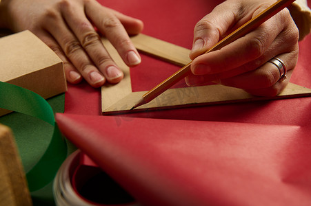 金额丝带摄影照片_用木尺特写女人的手，计算包装圣诞礼物所需的包装材料量